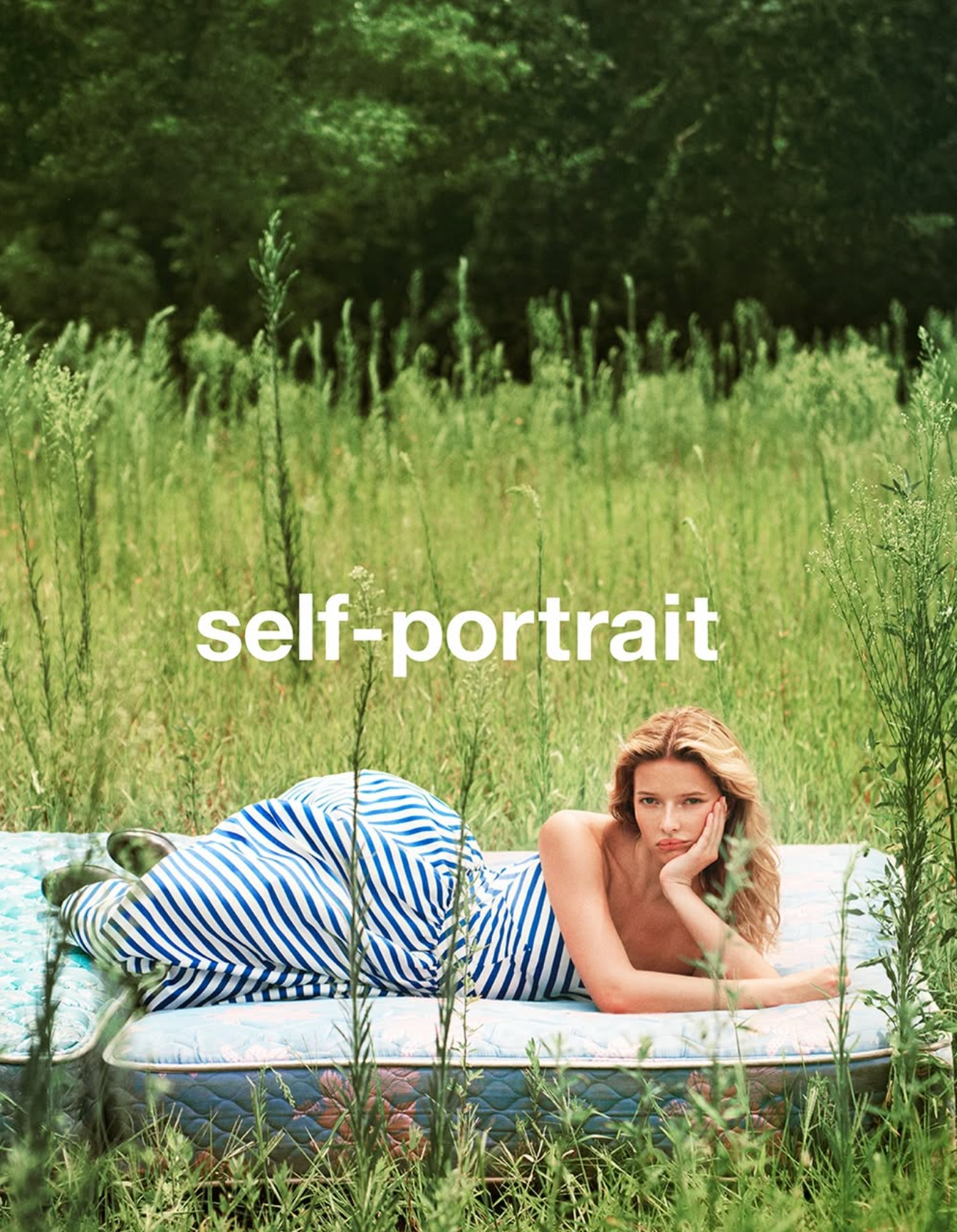 Woman lying on a mattress in a grassy field with 'self-portrait' text overlay