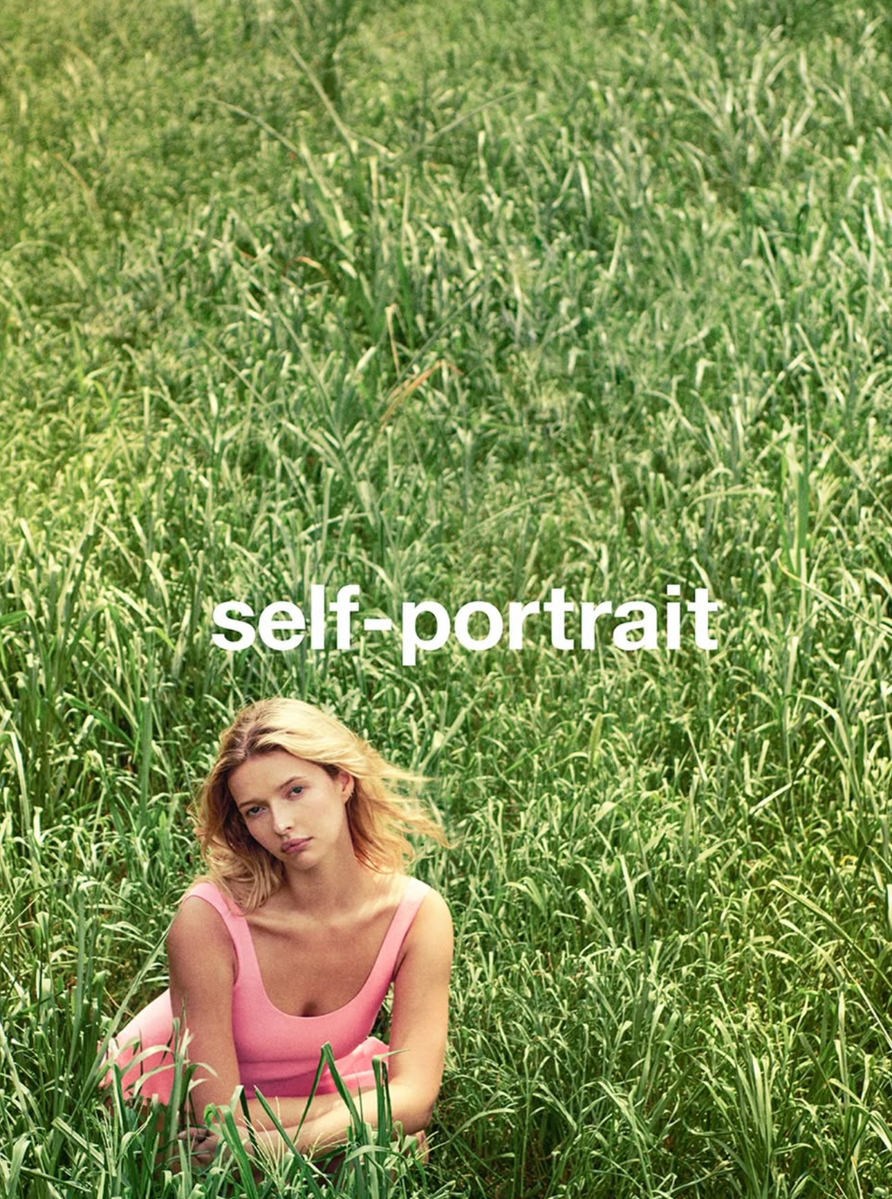 Woman in a pink top sitting in a grassy field with 'self-portrait' text overlay.