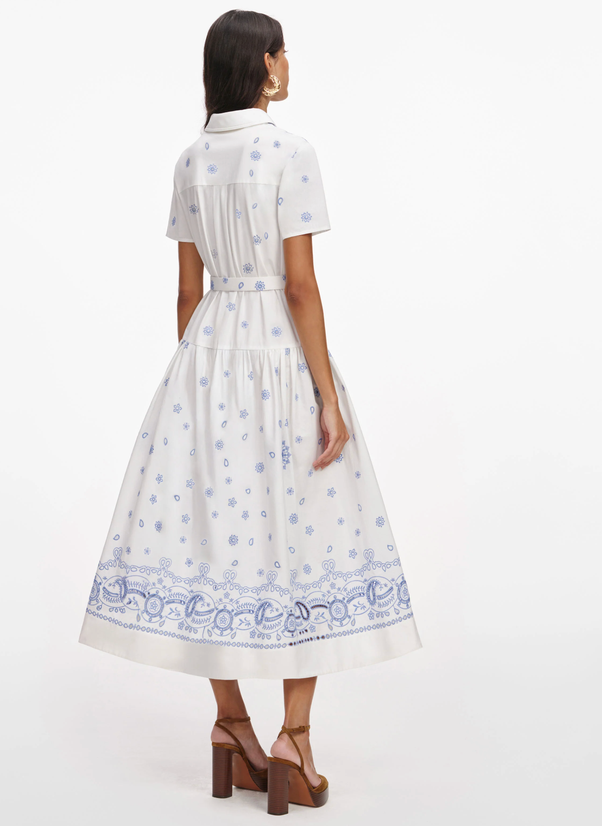Woman wearing a white dress with blue patterns on a white background