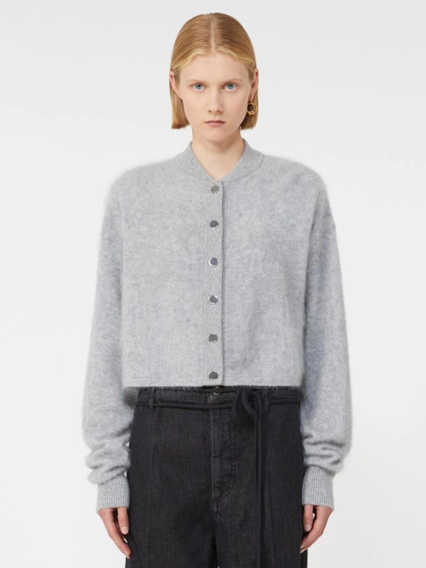 Person wearing a gray cardigan and black pants on a white background