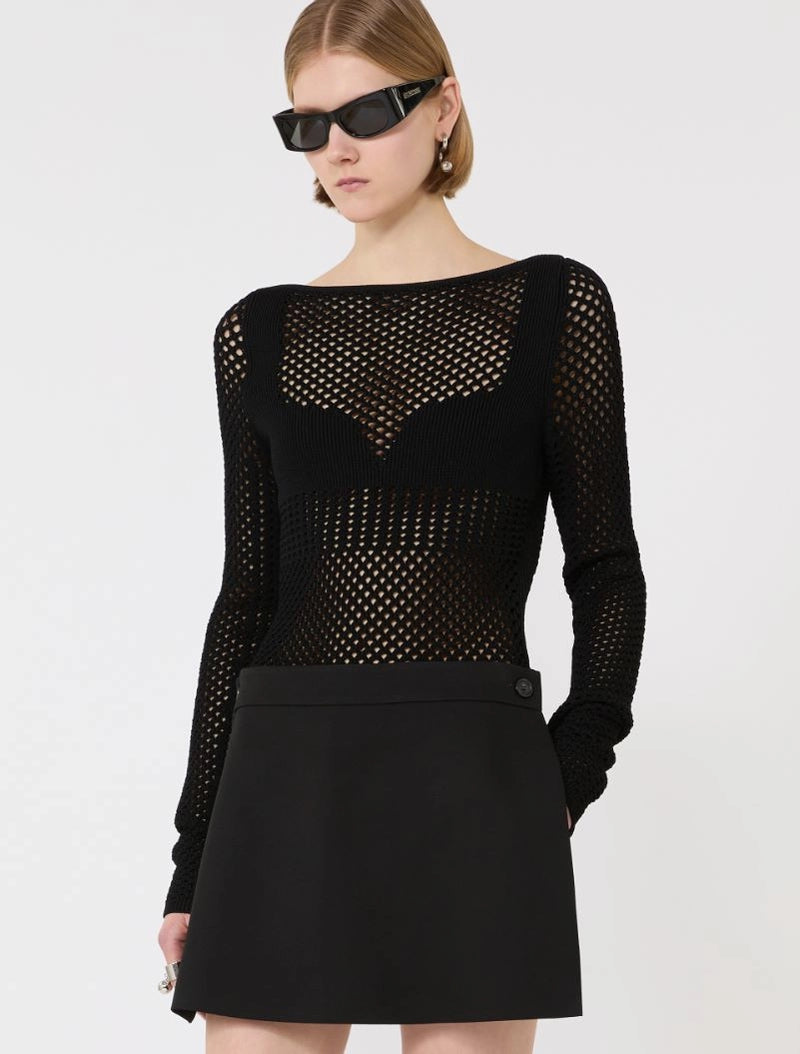 Model wearing a black mesh top and black skirt with sunglasses on a white background