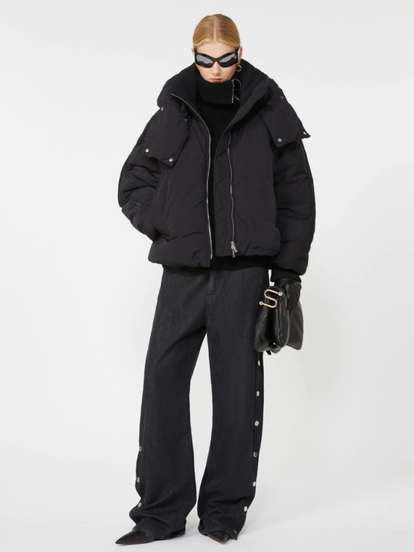 Person wearing a black puffer jacket and pants on a white background