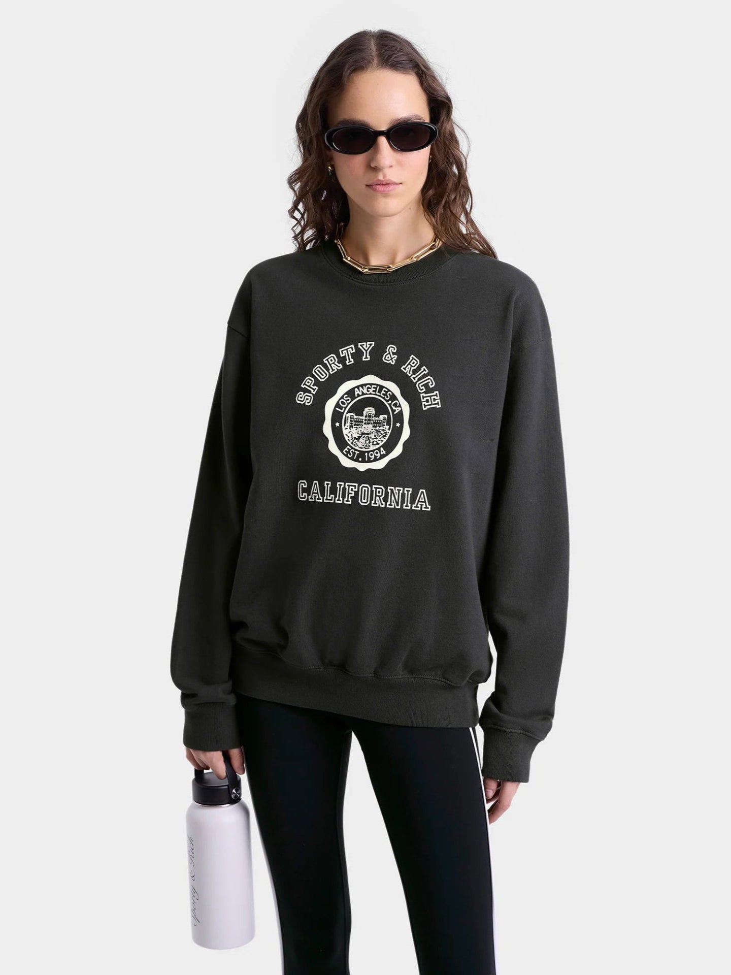 Person wearing a black sweatshirt with branding on a white background
