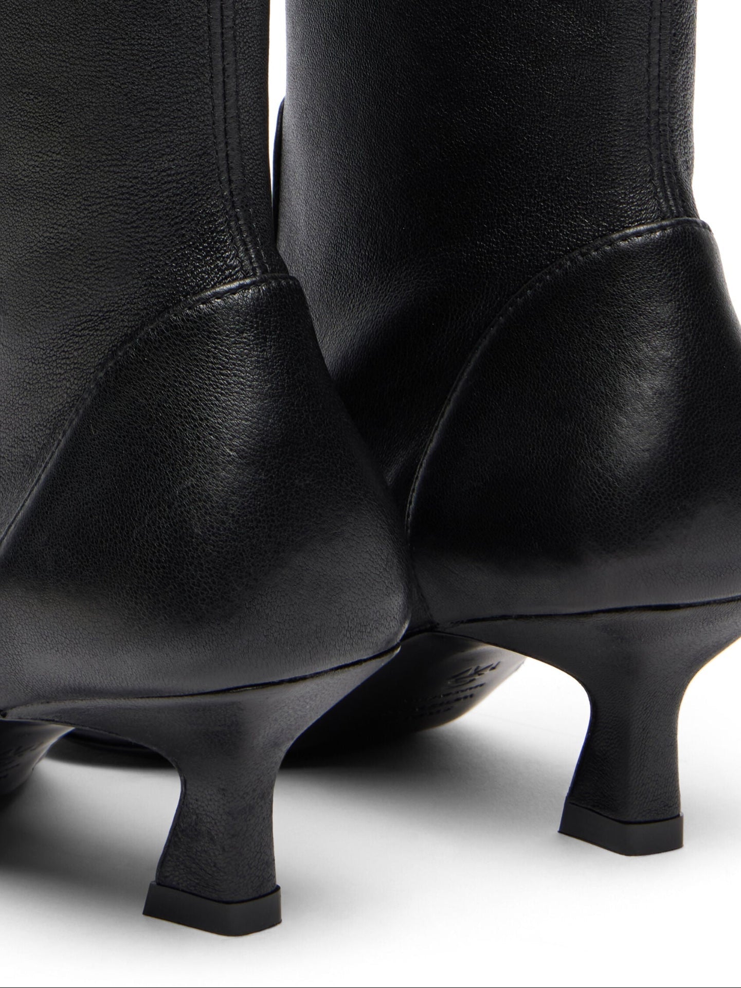 Black knee-high boots with thin heels on a white background