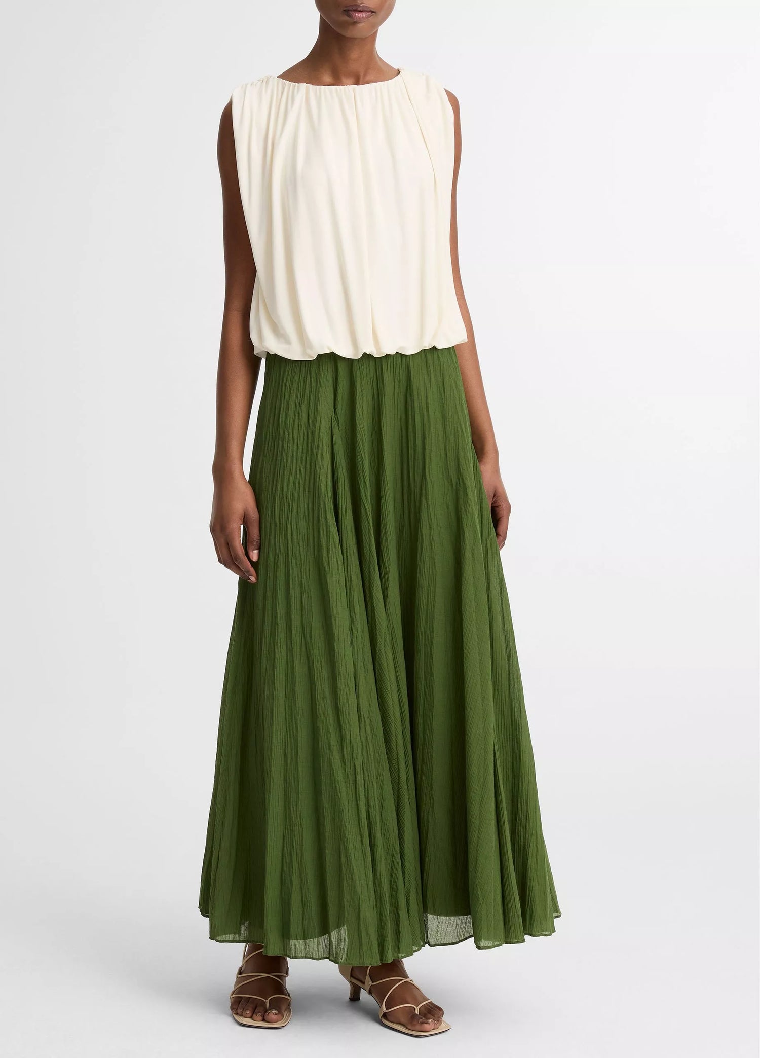 Person wearing a white top and green skirt on a white background