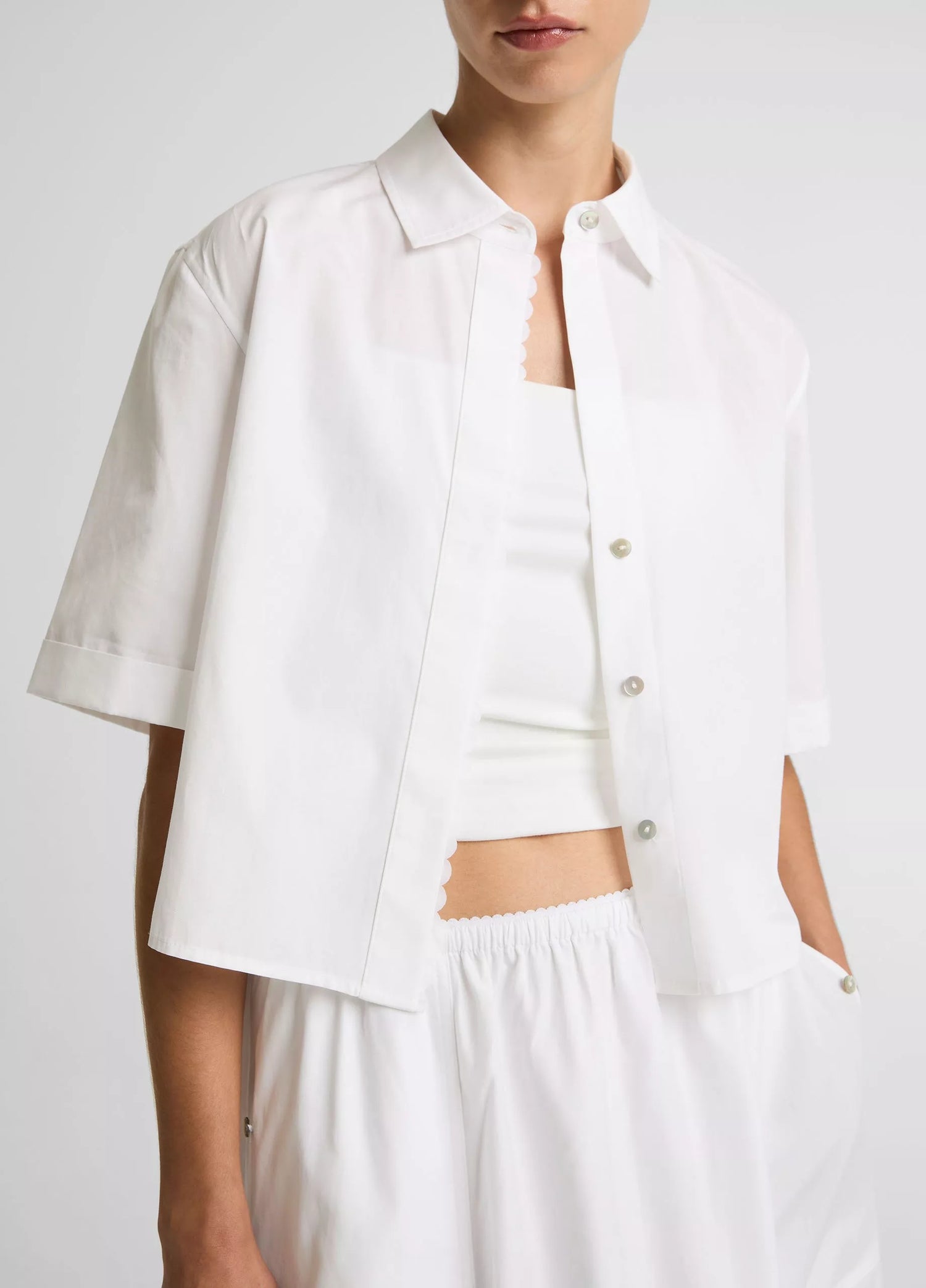 Person wearing a white button-up shirt and pants on a plain background