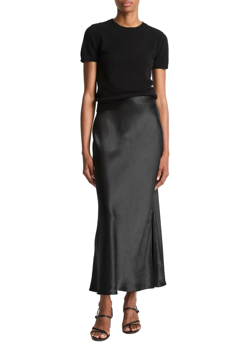 Person wearing a black top and black satin skirt from Vince