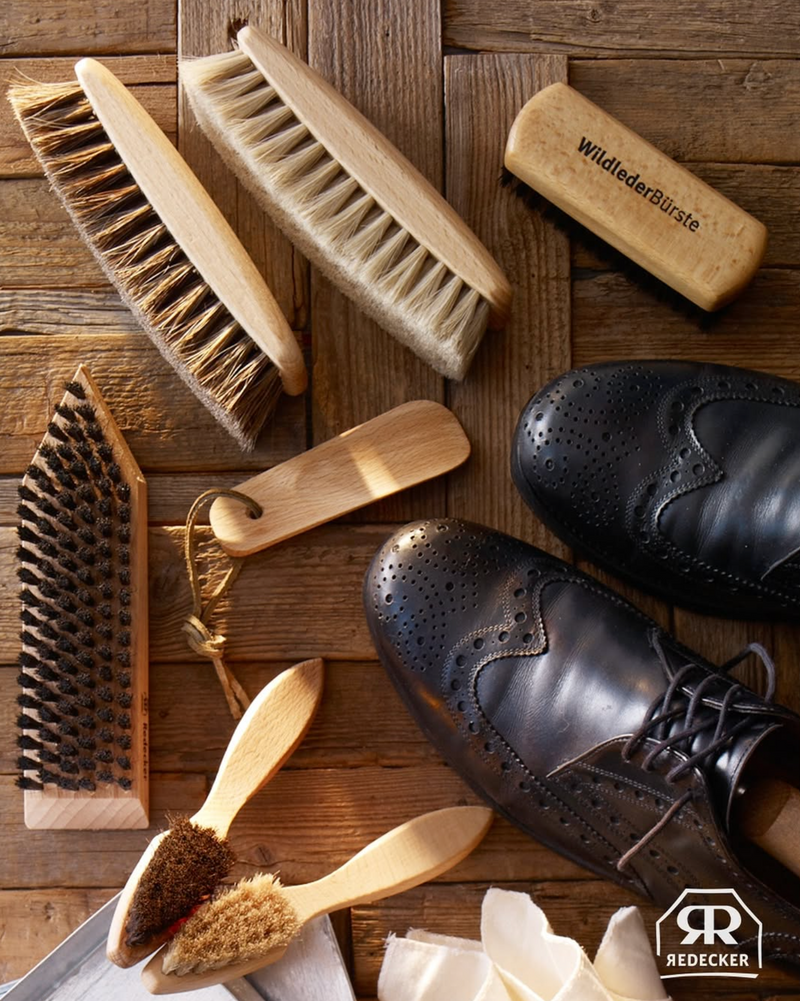 Set of shoe cleaning brushes and tools on a wooden surface with Redecker branding.