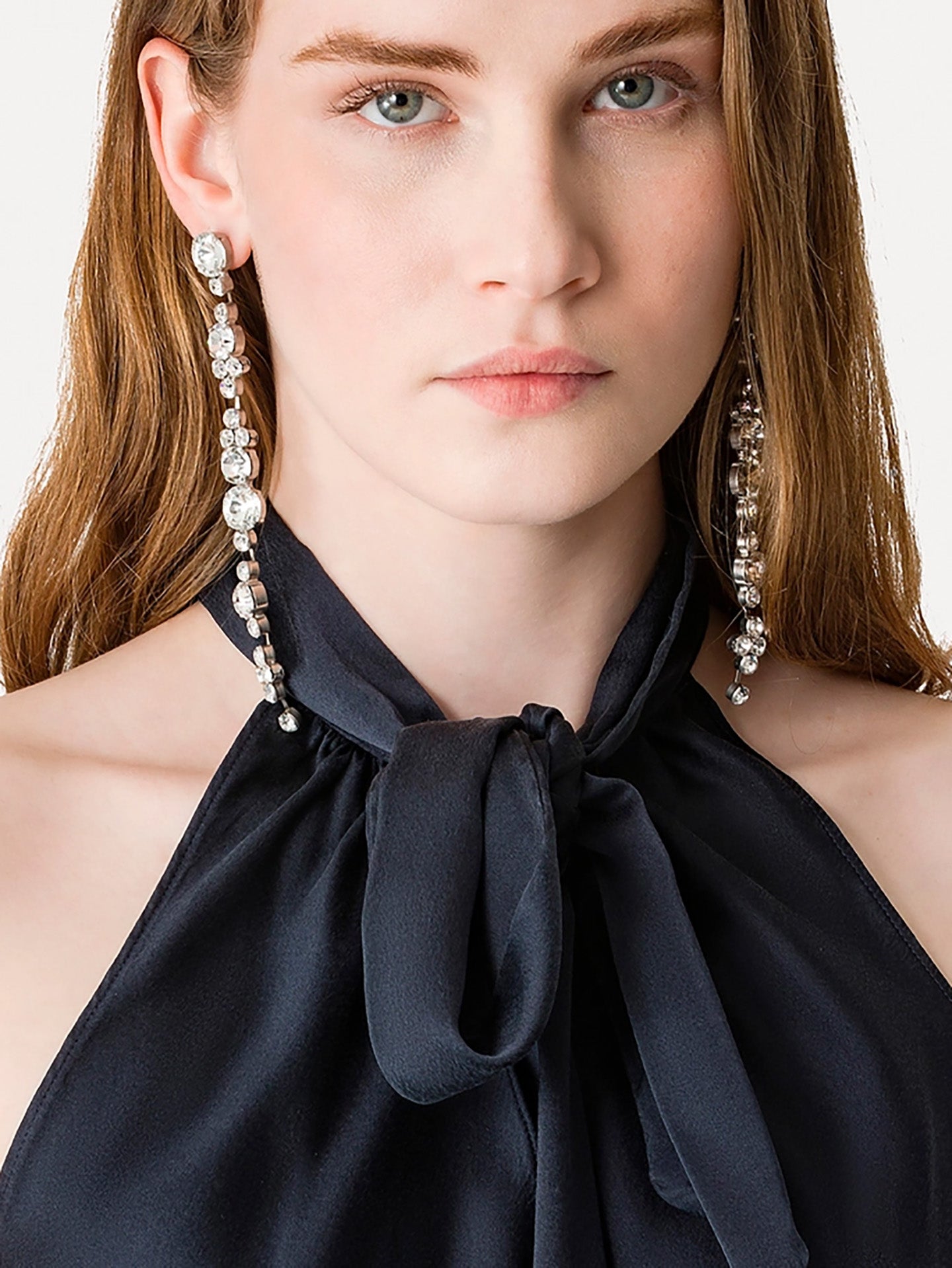 Close-up of a woman wearing elegant earrings with a plain background