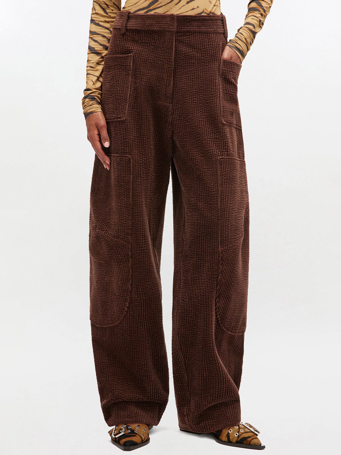 Brown corduroy pants worn by a person on a white background