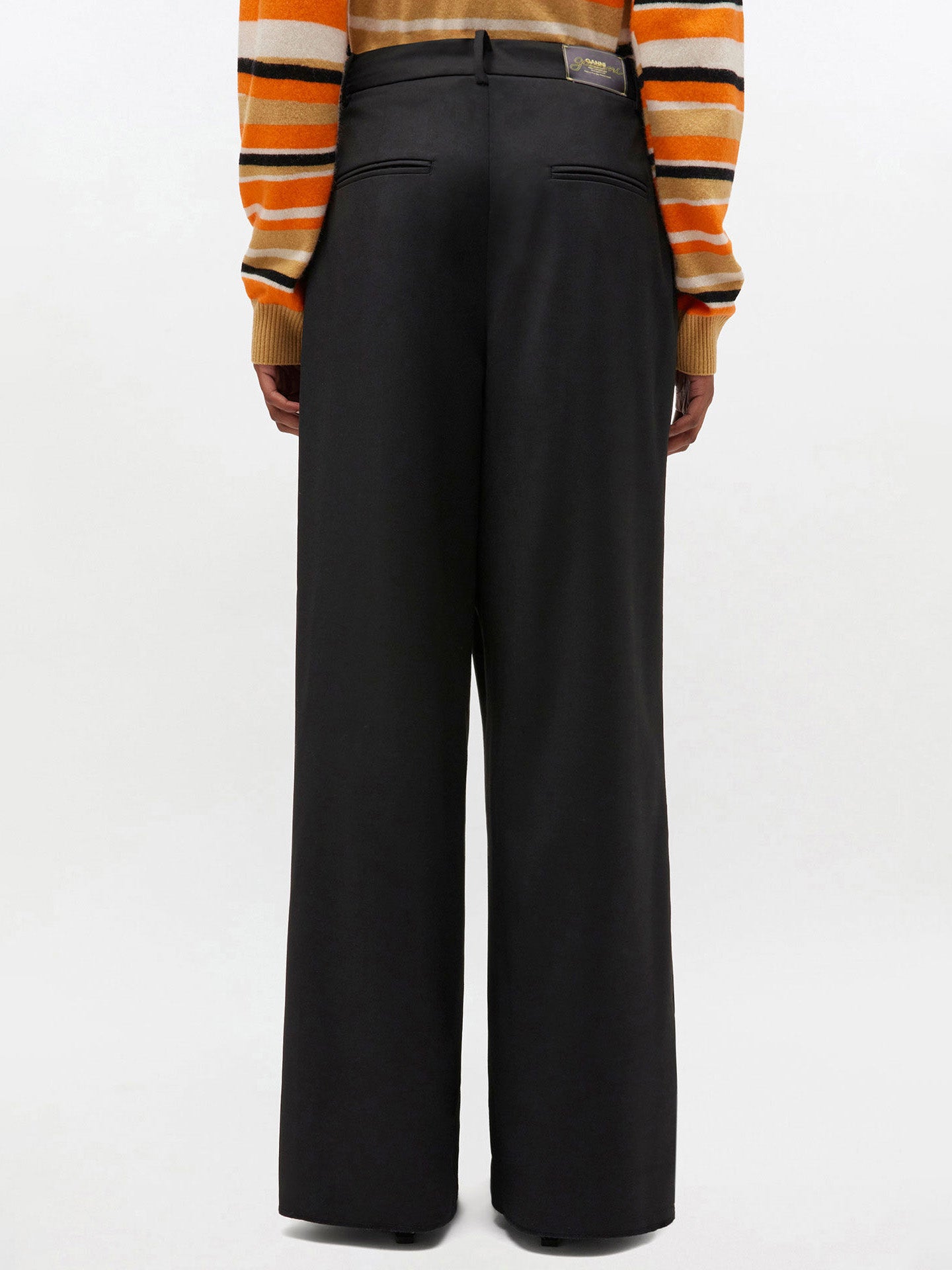 Person wearing black wide-leg pants with a striped shirt on a white background