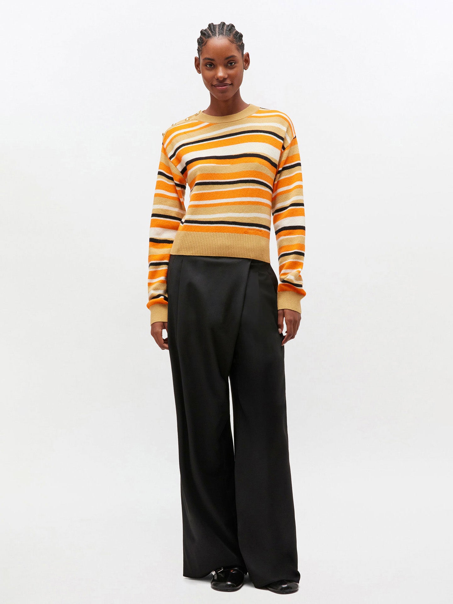 Person wearing a striped sweater and black pants on a white background