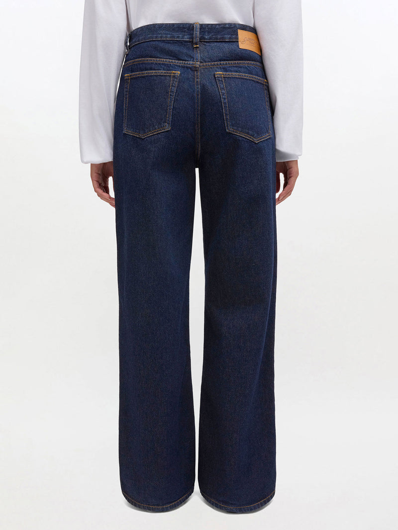 Dark blue jeans worn by a person on a white background