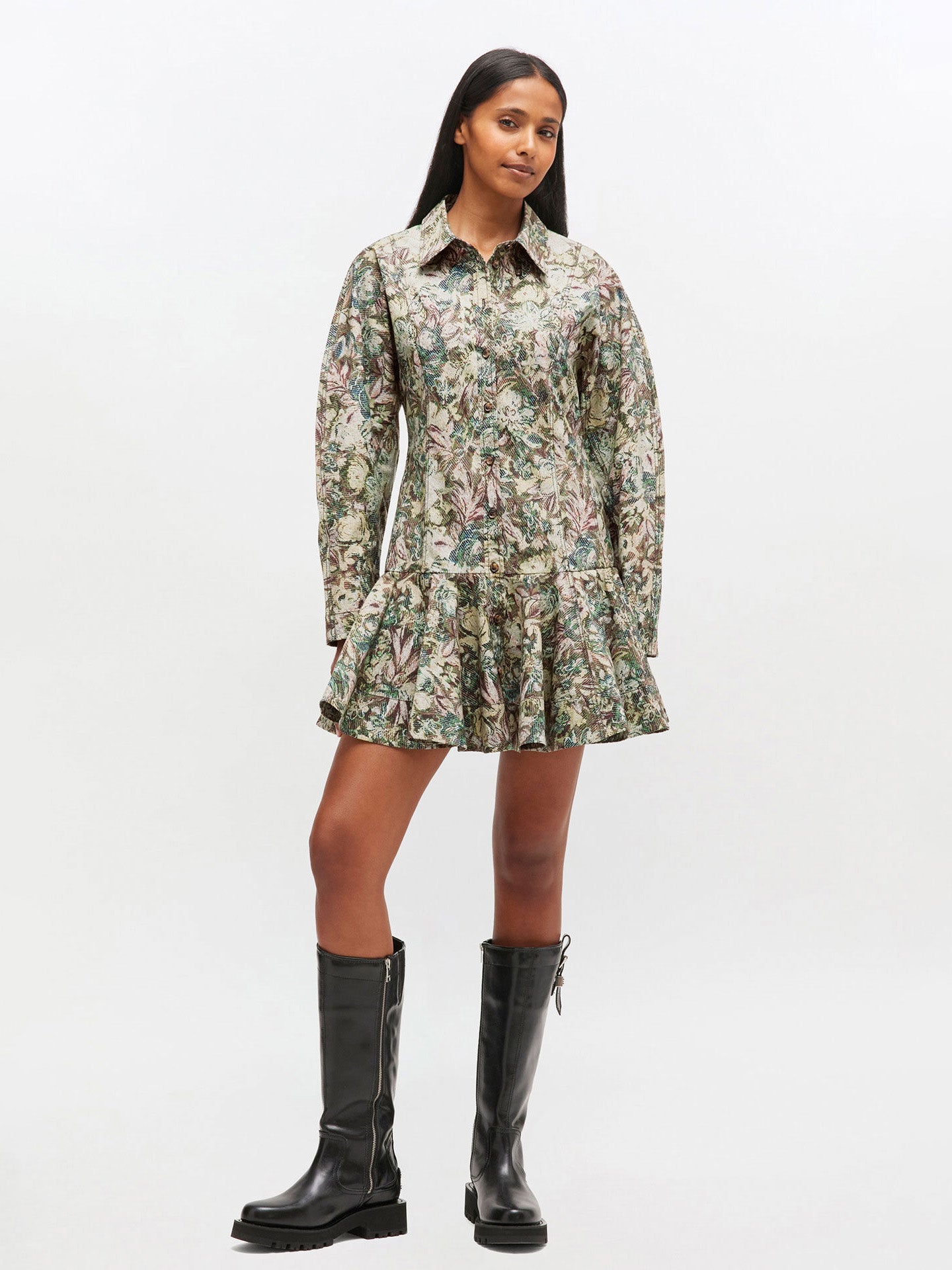 Woman wearing a floral dress and black knee-high boots on a white background