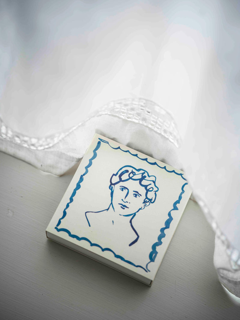 Small square tile with blue line art of a face on a white background
