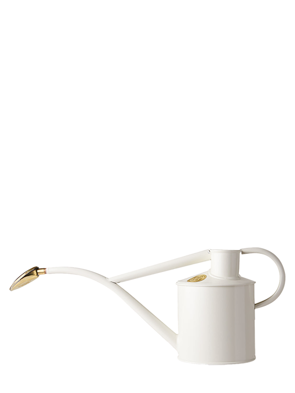 A white metal watering can with a long curved spout and a brass rose, handcrafted to resemble a century old design.