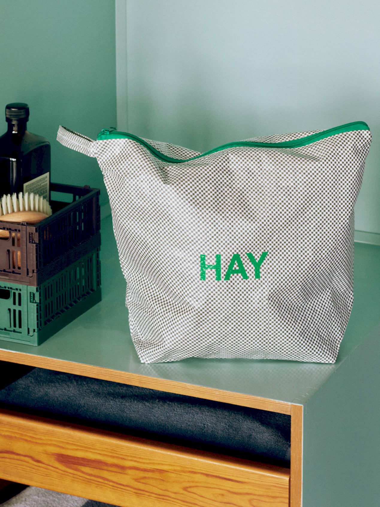 Toiletry bag with 'HAY' branding on a green surface