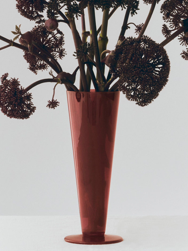 Red vase with dried flowers on a light gray background