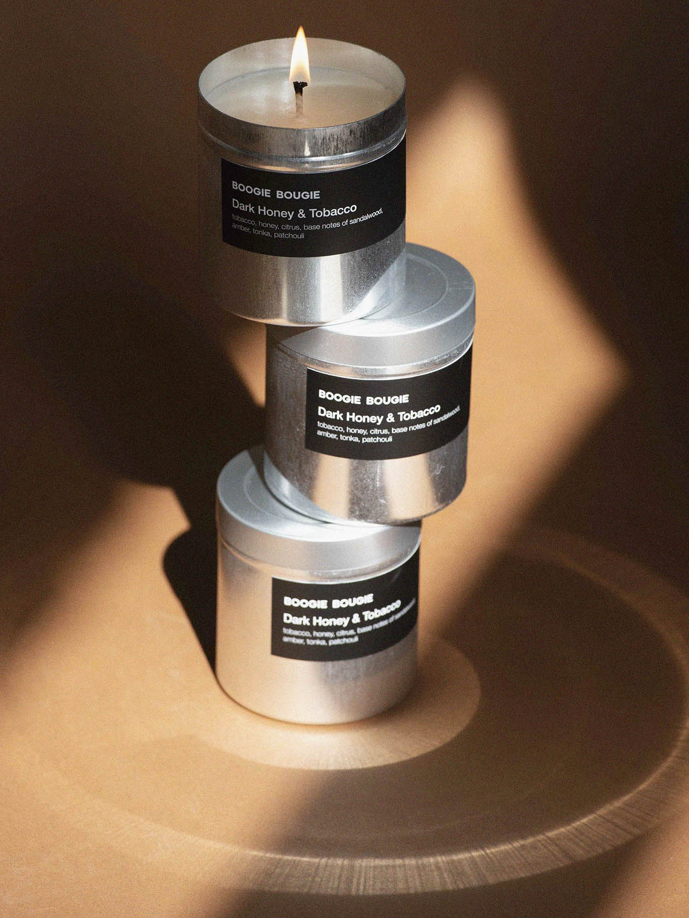 Stack of three candles with labels on a wooden surface