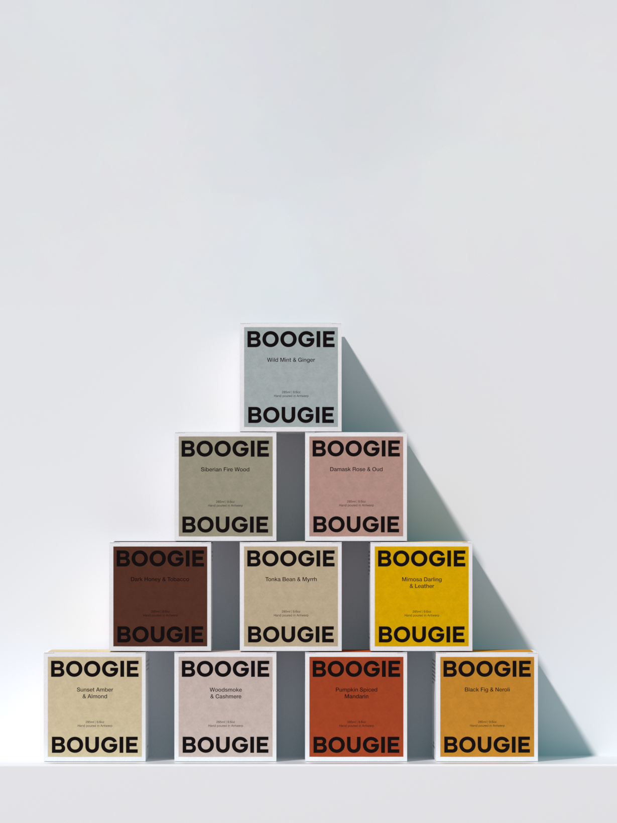Collection of 'Boogie Bougie' scented candle boxes in various colors on a light gray background