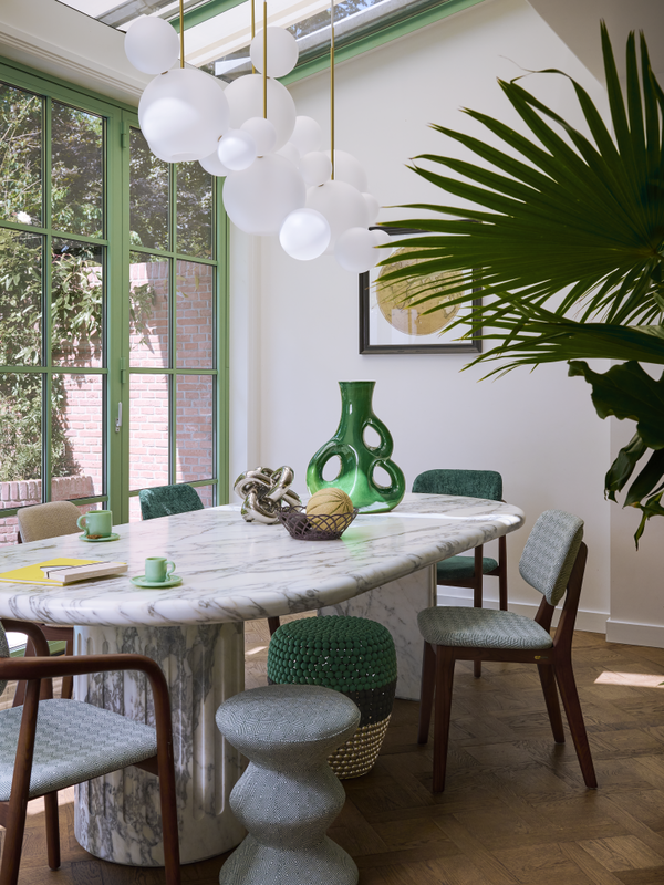 Dining room with marble table, green chairs, and decorative elements.
