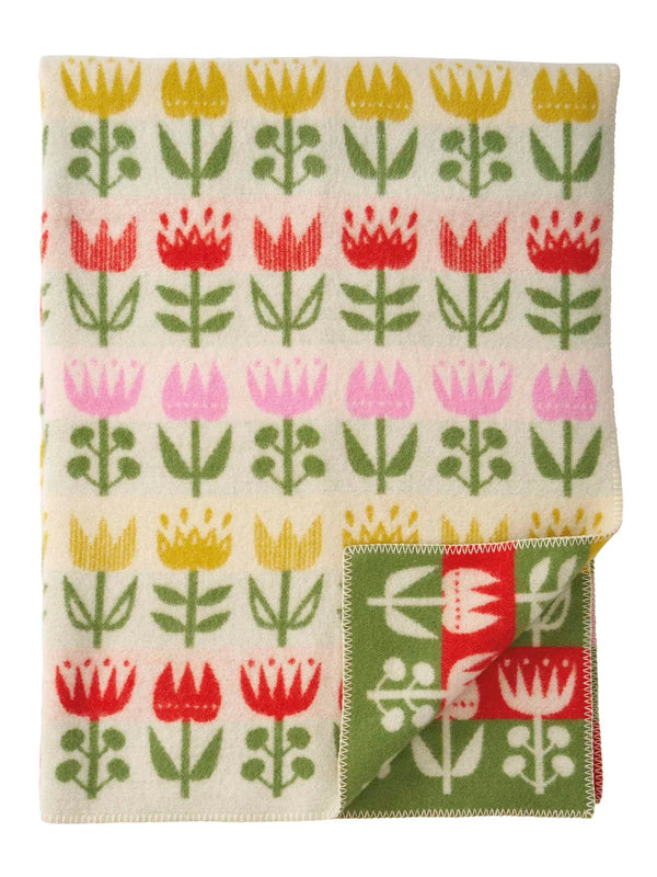 Tulip patterned wool throw with a folded corner on a white background