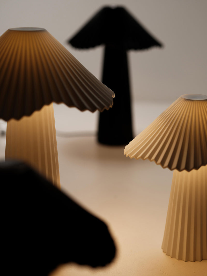 Two pleated paper lamps on a light background with a black silhouette of an arrow.