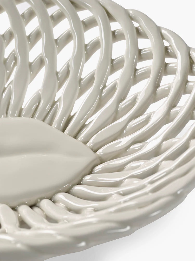 Close-up of a white ceramic bowl with woven design on a light background