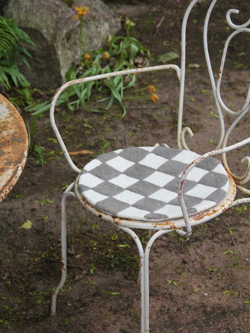 Rustic white metal chair with checkered cushion on a garden setting