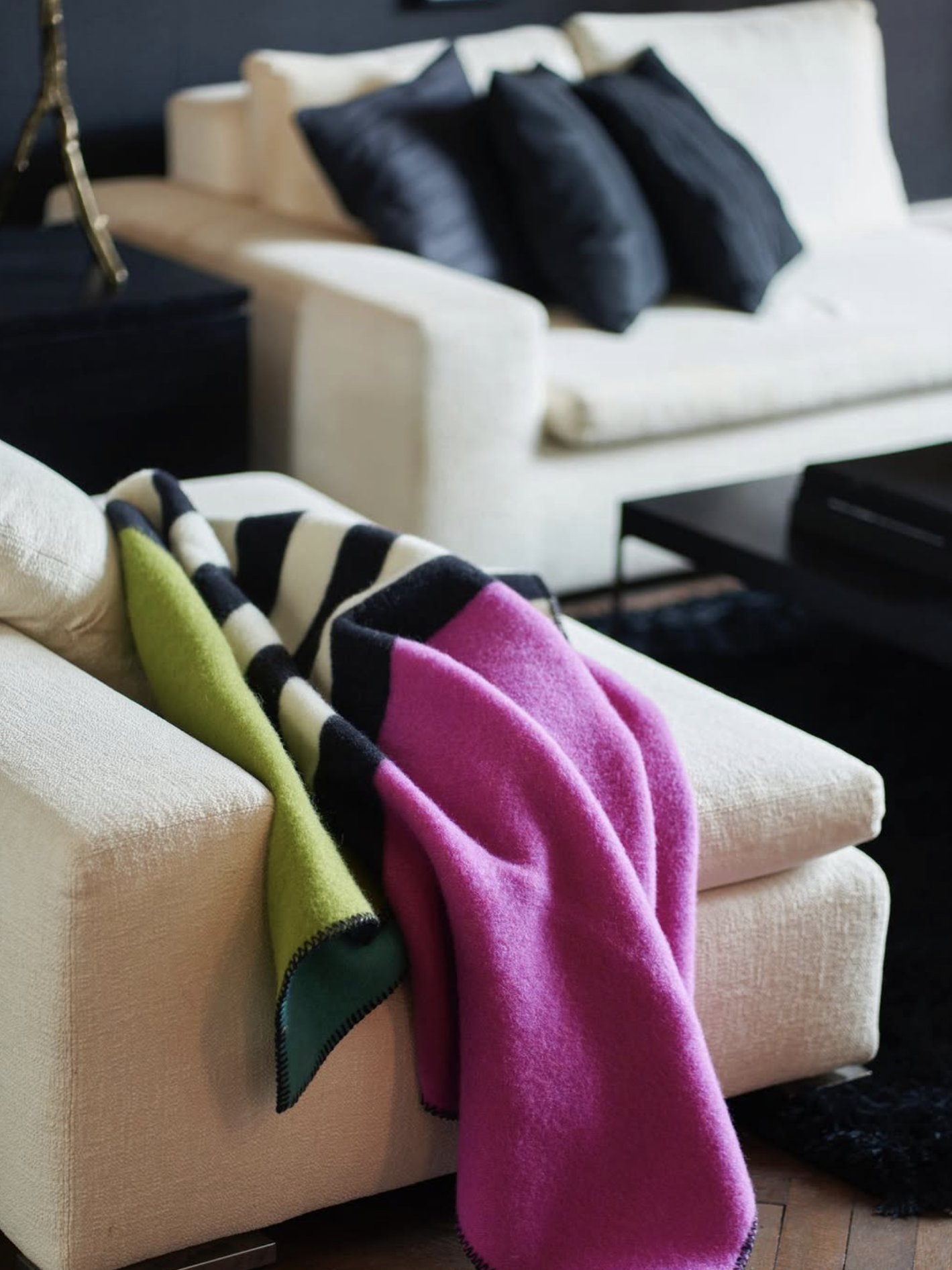 Colorful blanket draped over a beige sofa in a living room setting.