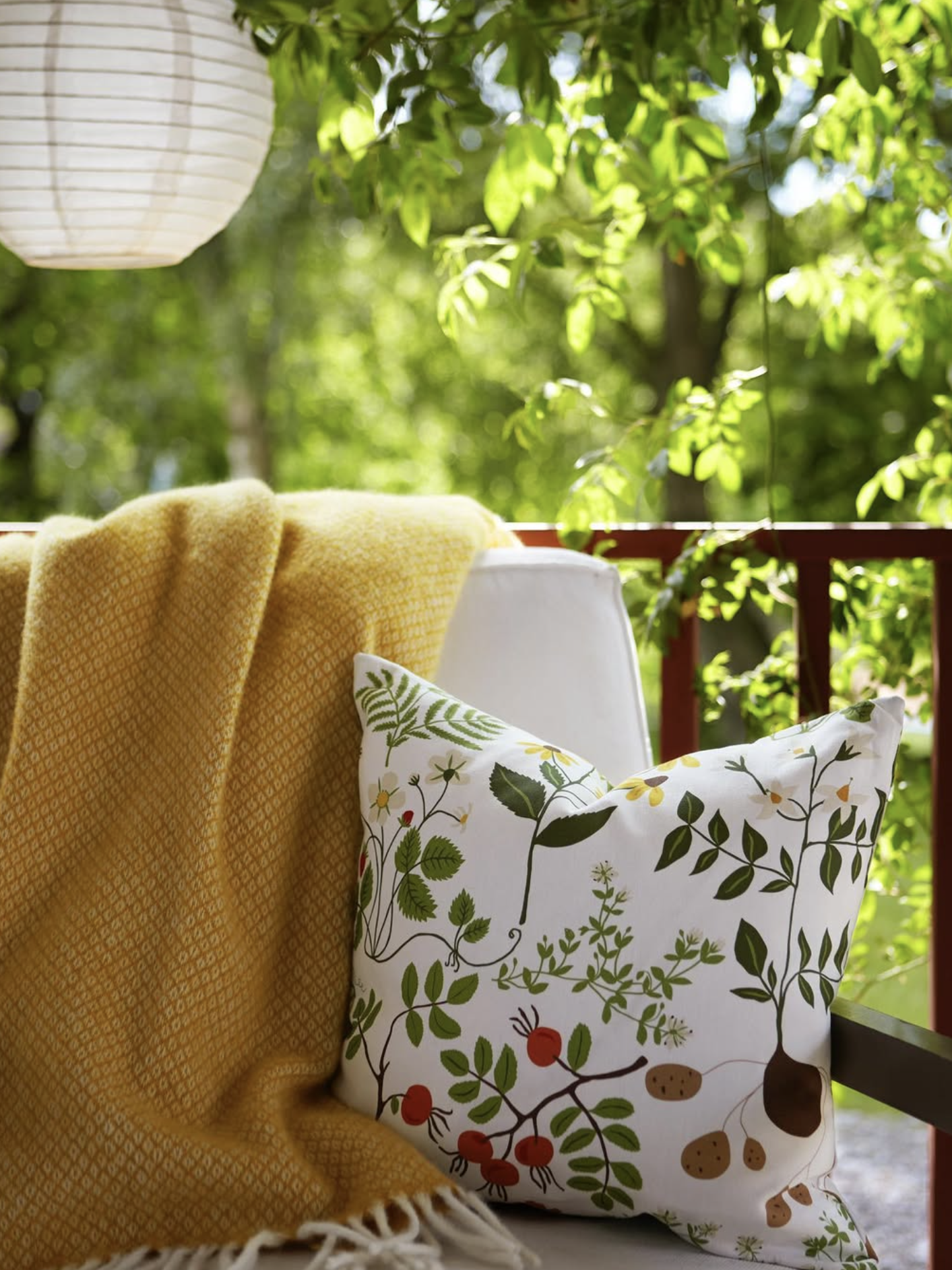 Decorative pillow with nature pattern on a chair with yellow blanket, outdoor setting