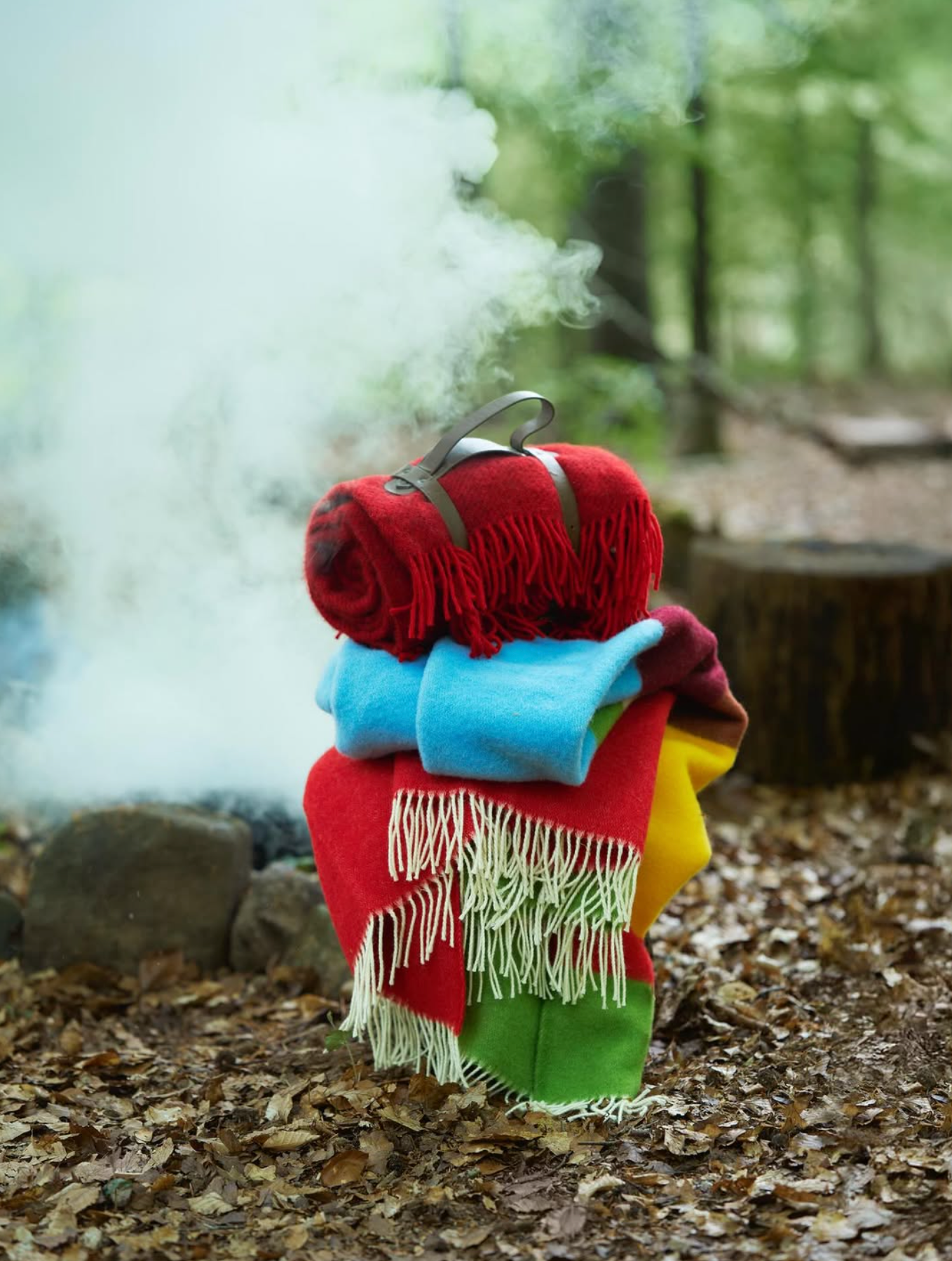 Stack of colorful blankets on a log in a forest setting