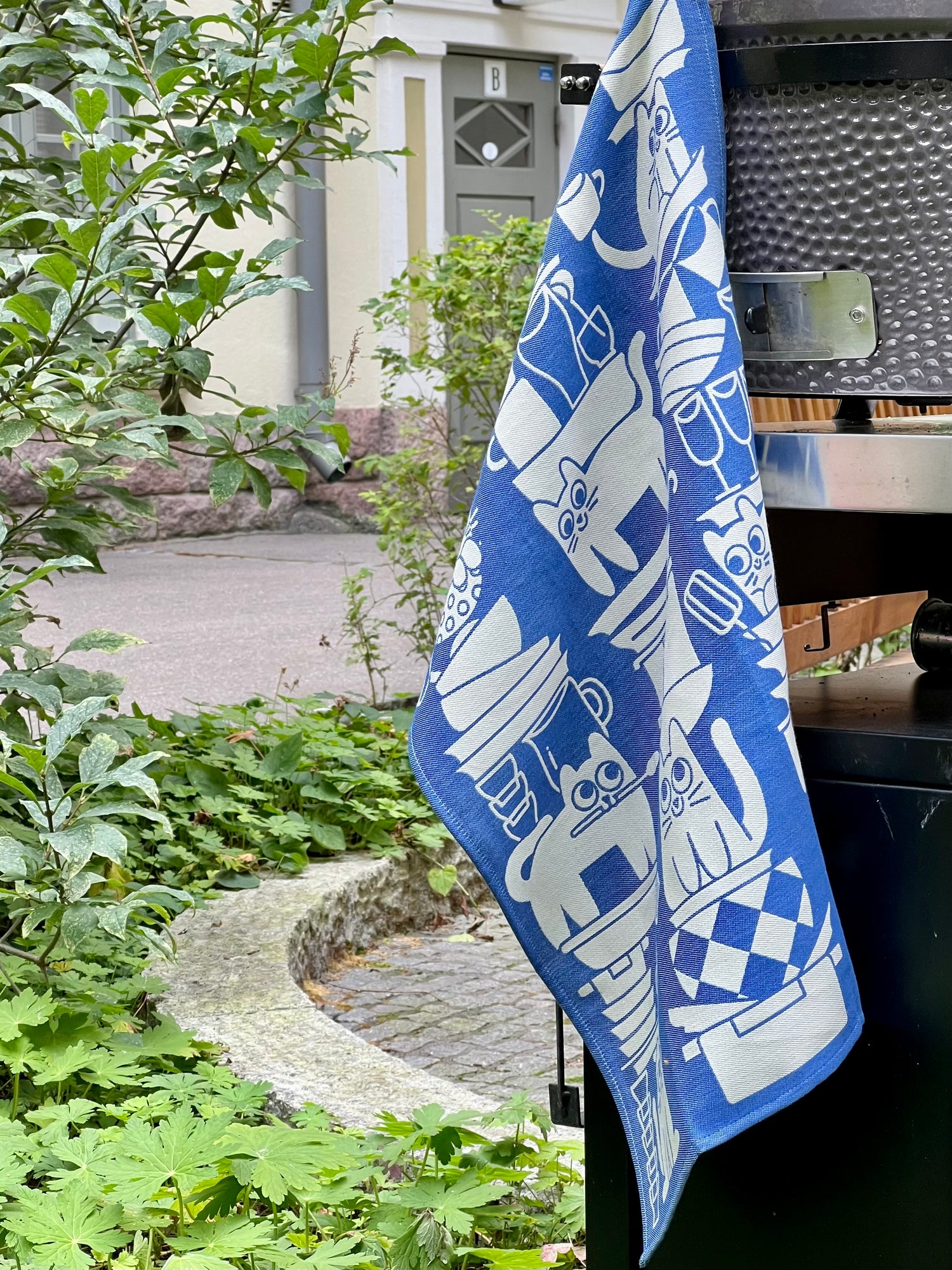 Blue towel with white designs hanging on a grill outdoors