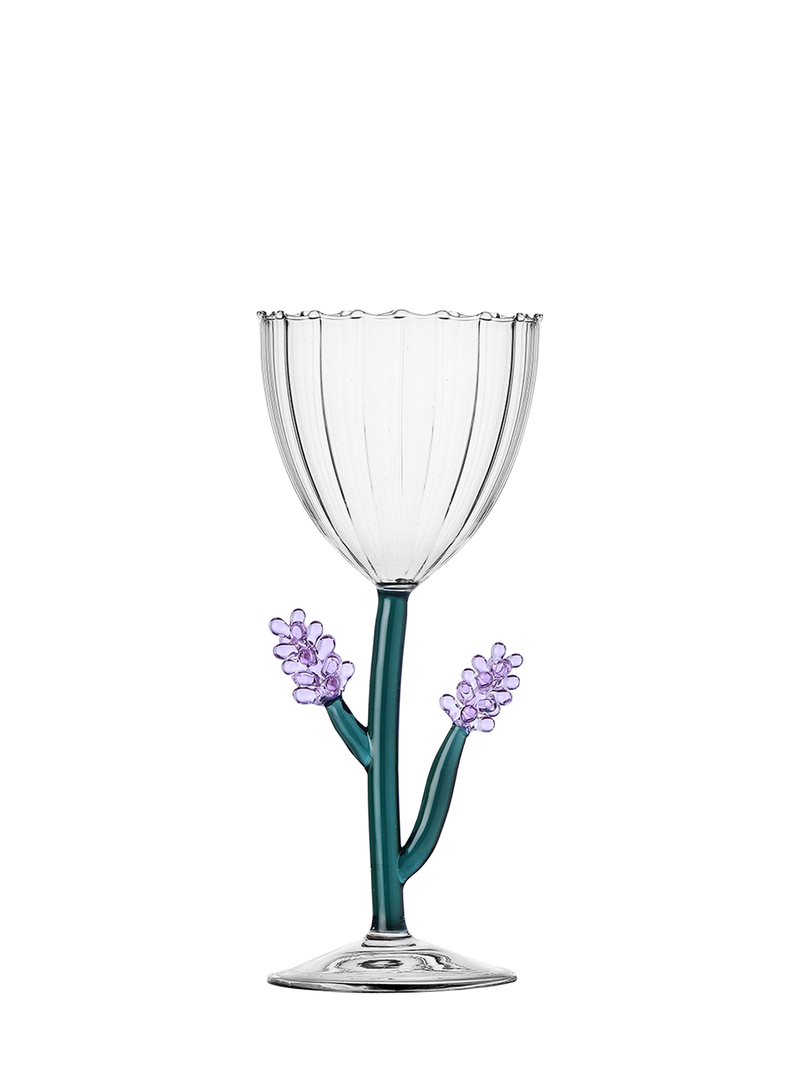 A clear wine glass with a pleated texture and a cookie-cutter shaped rim, featuring a petrol green stem with two small hand-formed lavender flowers in light purple.