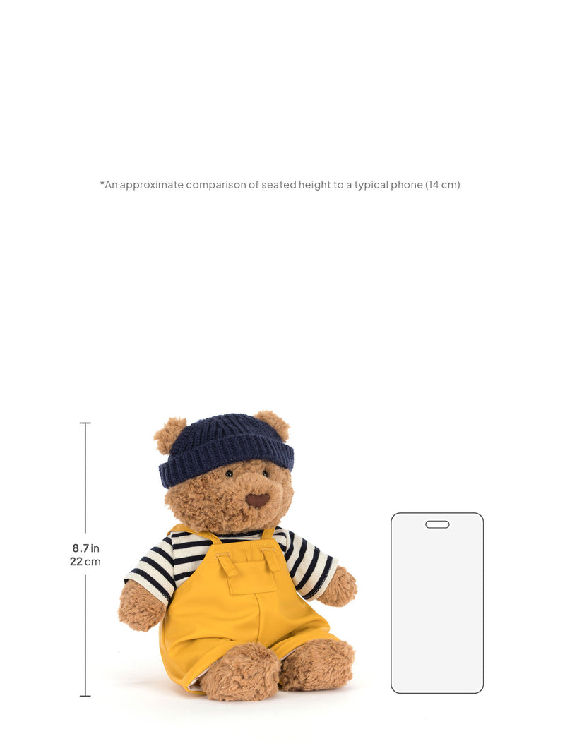 Plush bear toy with a smartphone for size comparison on a white background
