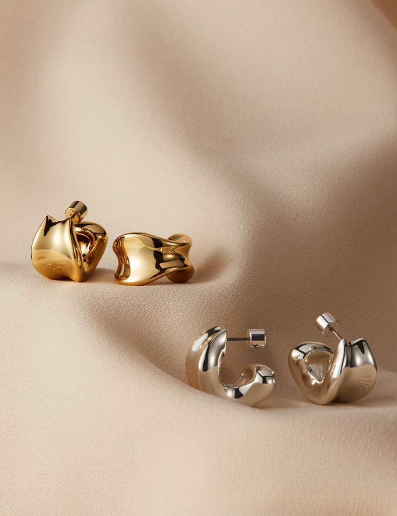 Gold and silver earrings on a beige background