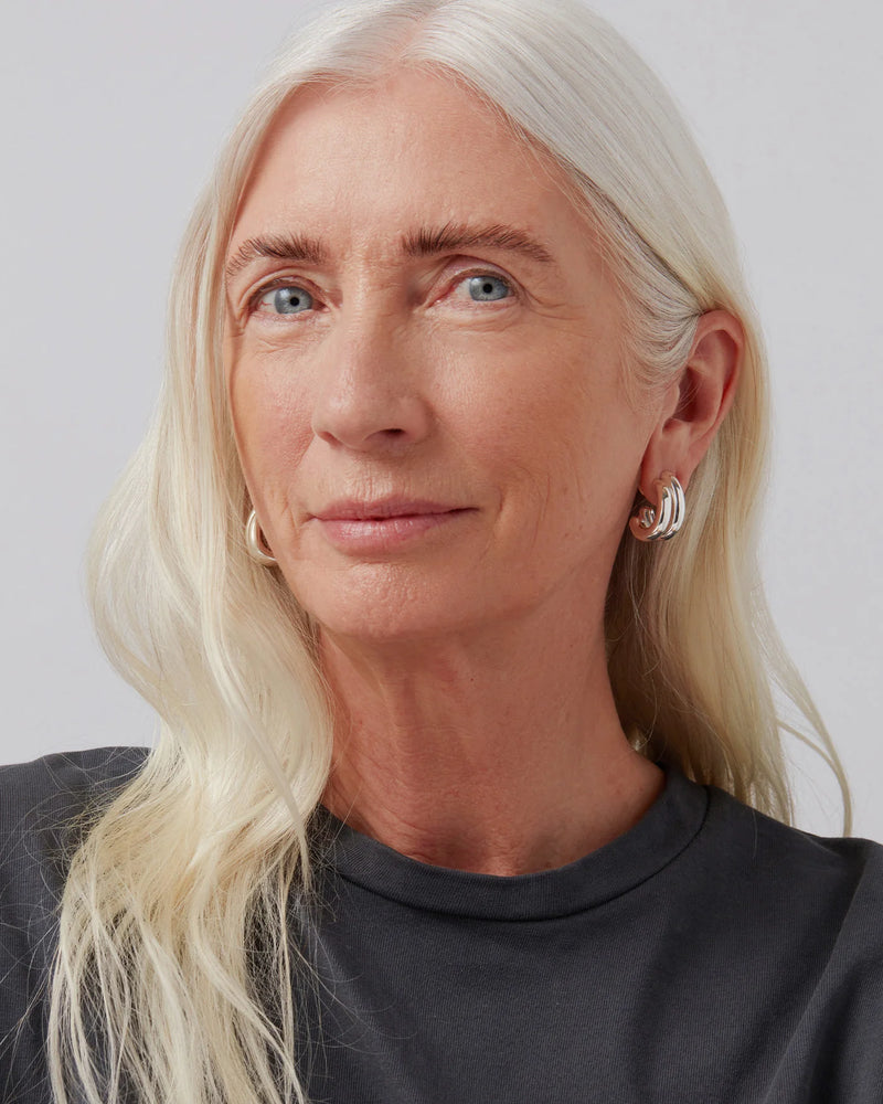 Person with long blonde hair wearing silver earrings