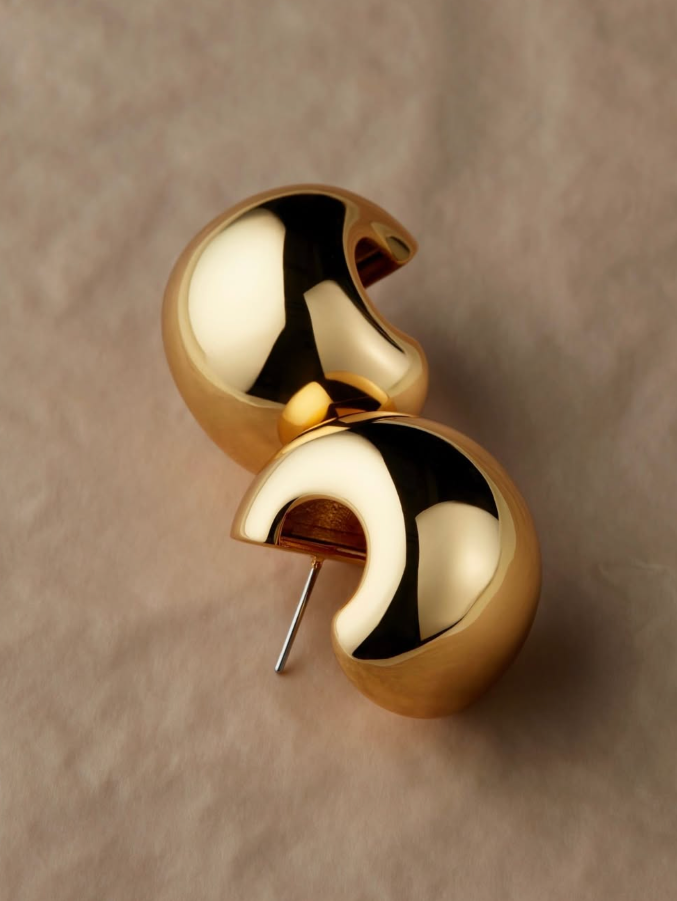 Gold half-circle earring on a beige background