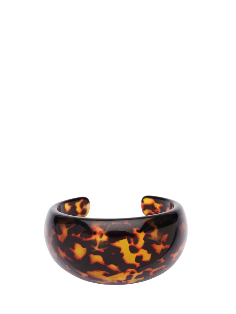 A glossy tortoiseshell cuff bracelet with a black and amber-orange mottled pattern, photographed on a solid white background.