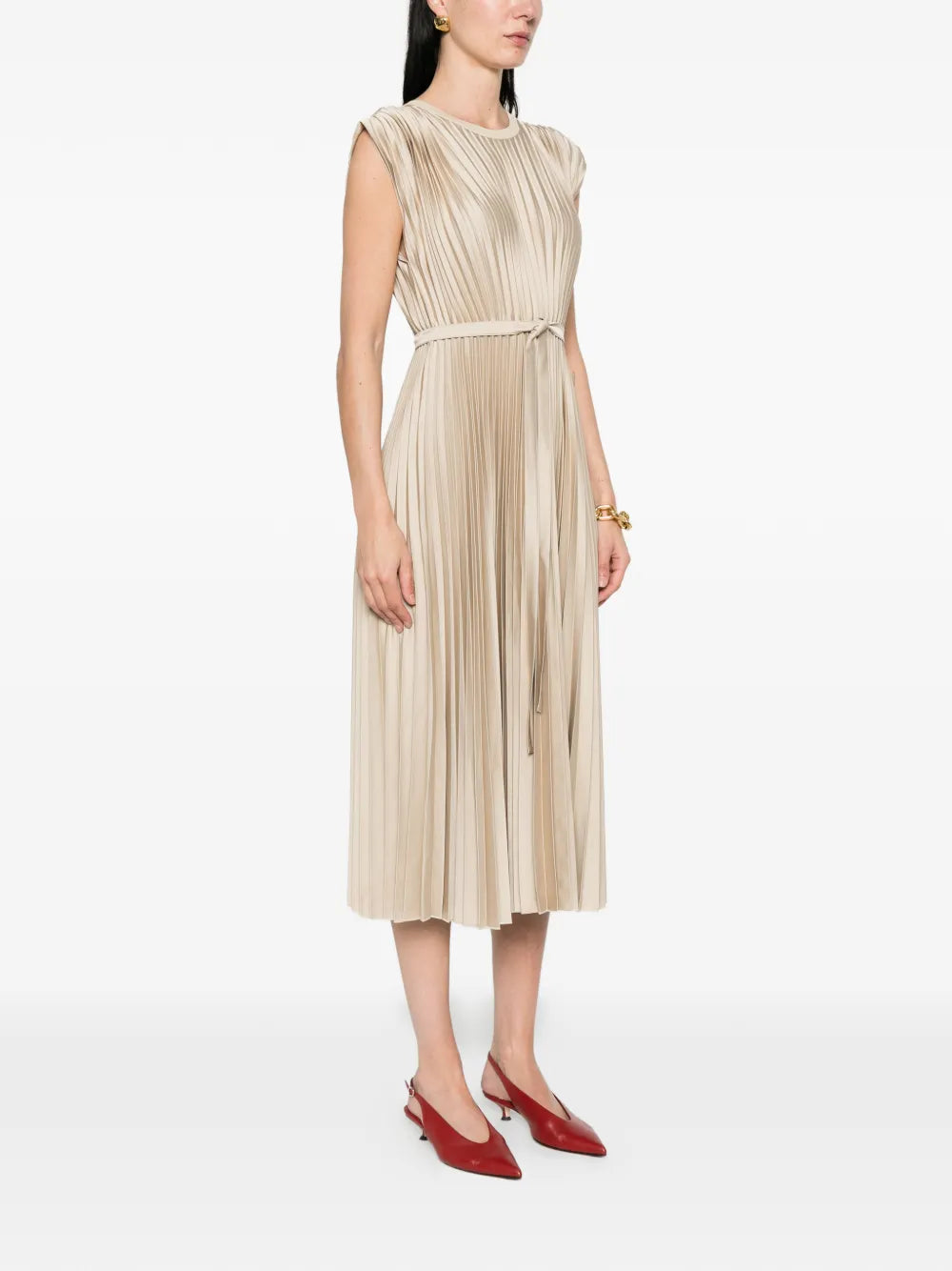 Woman wearing a beige pleated dress with red shoes on a white background