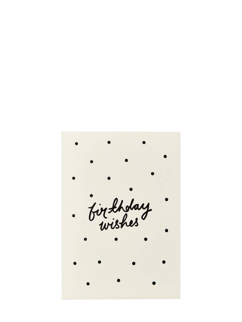A cream-coloured greeting card with a black polka dot pattern and the words 'birthday wishes' written in black cursive script in the center, shown against a plain white background.