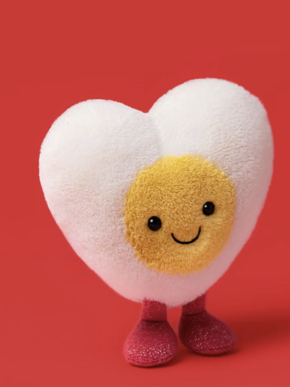 Heart-shaped plush toy with a smiling face on a red background
