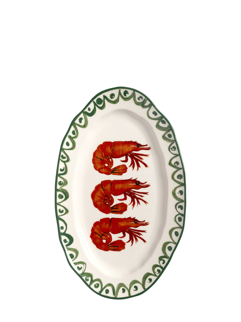 An oval white serving platter featuring three red prawns in the center and a green patterned border, set against a plain white background.