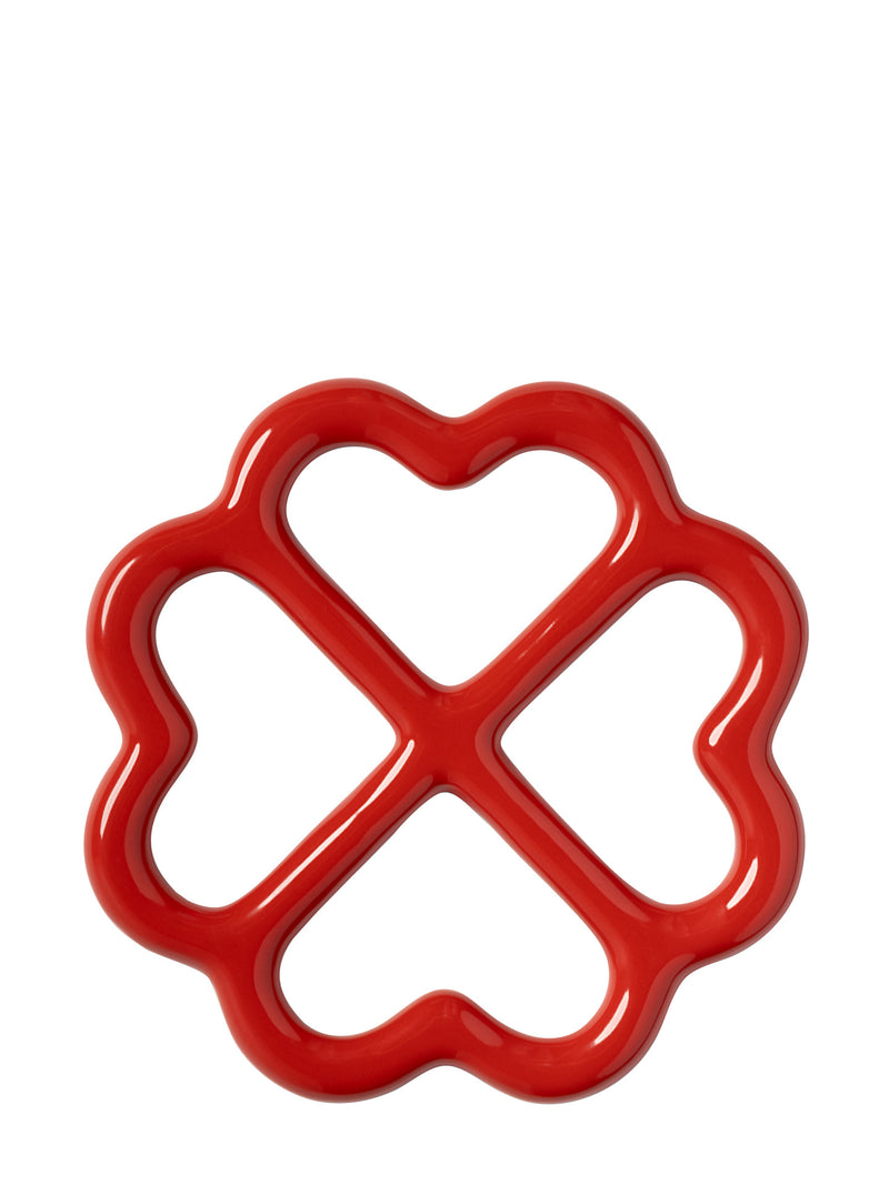 A glossy red ceramic trivet with a wavy flower-like border and four heart-shaped cutouts, shown on a plain white background.