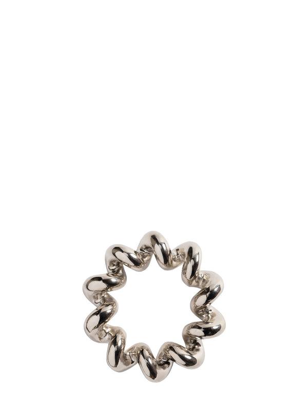 A silver metallic looking trivet with a wavy, segmented design, photographed on a solid white background.