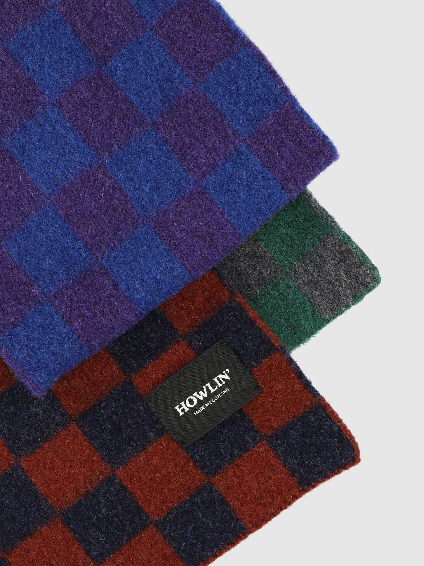 Four checkered scarf in blue, green, red, and black with a visible brand label on a light gray background.
