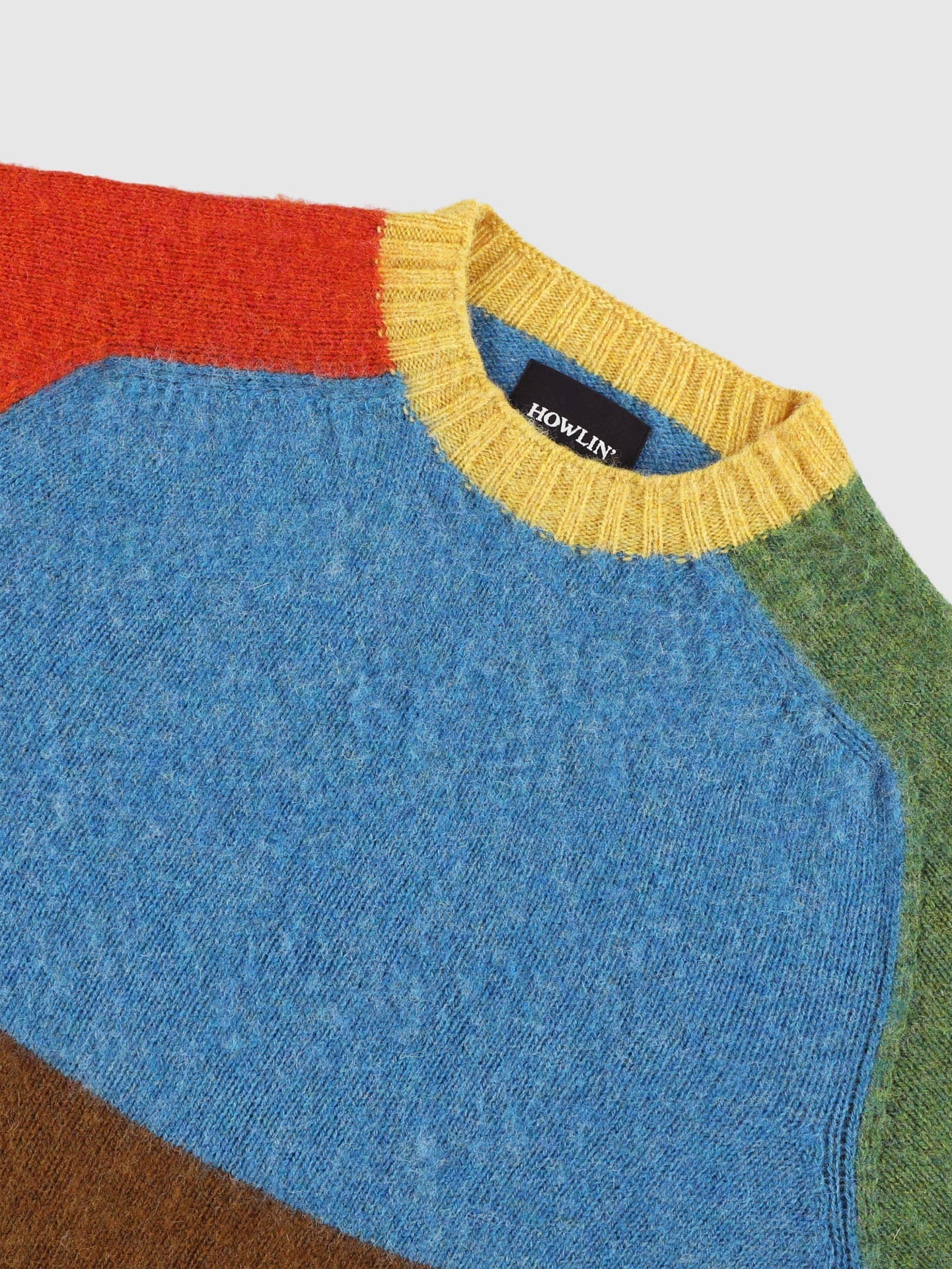 Color-blocked sweater with a visible brand logo on a light gray background