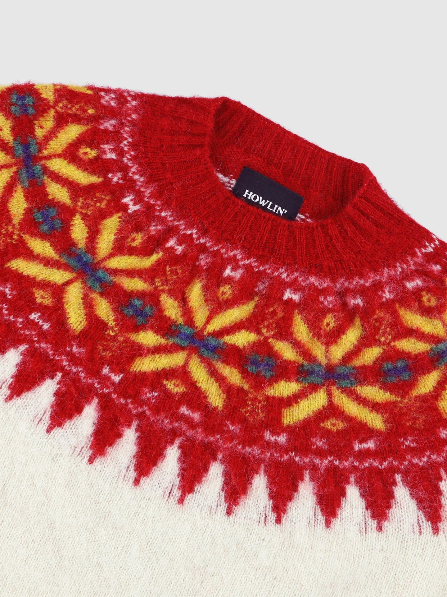 Red sweater with yellow and blue patterns on a white background, featuring the brand 'Howlin'.