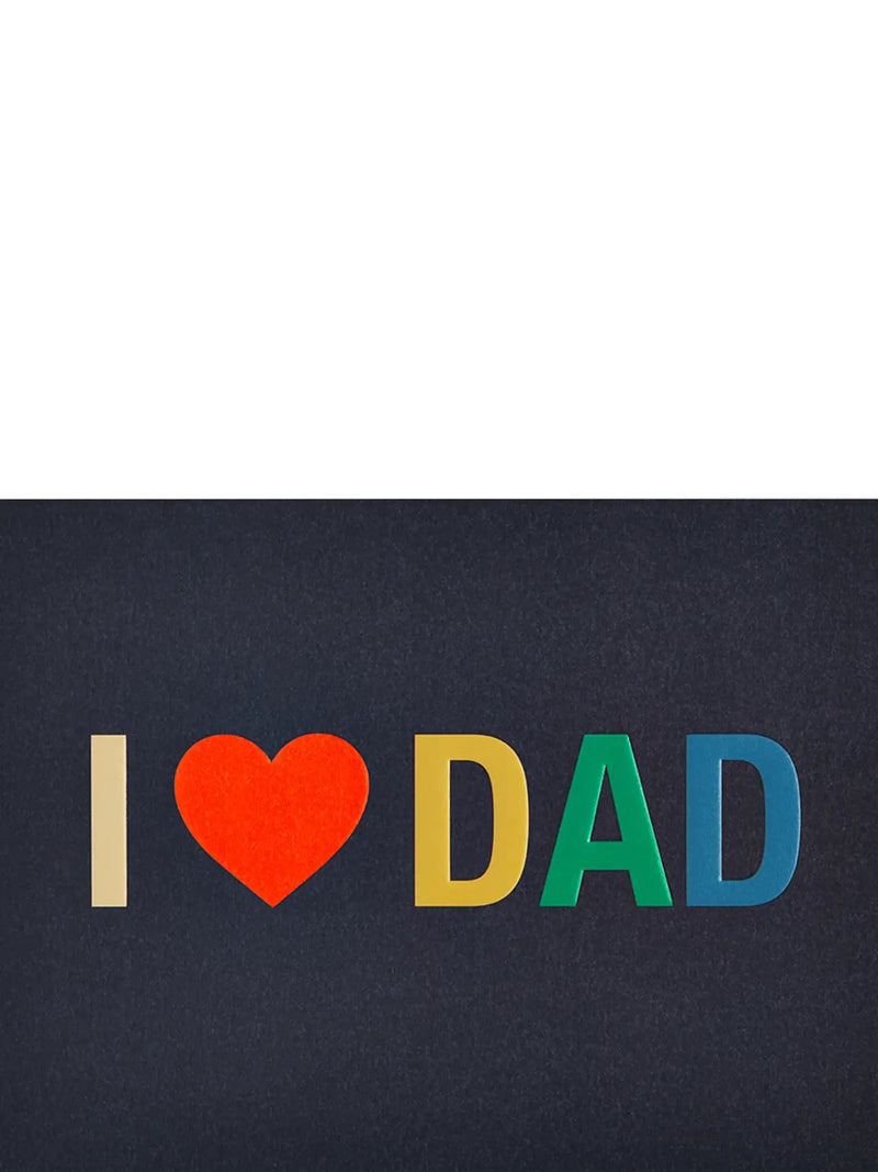 A square art print or card featuring the text 'I [heart] DAD' in colorful paper-cut letters on a dark charcoal background, with a large white negative space at the top.