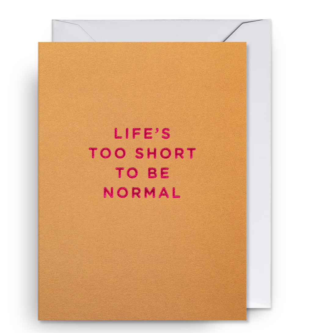 A mini sized greeting card with the text 'LIFE'S TOO SHORT TO BE NORMAL' printed on it, presented alongside a white envelope, all against a black background.